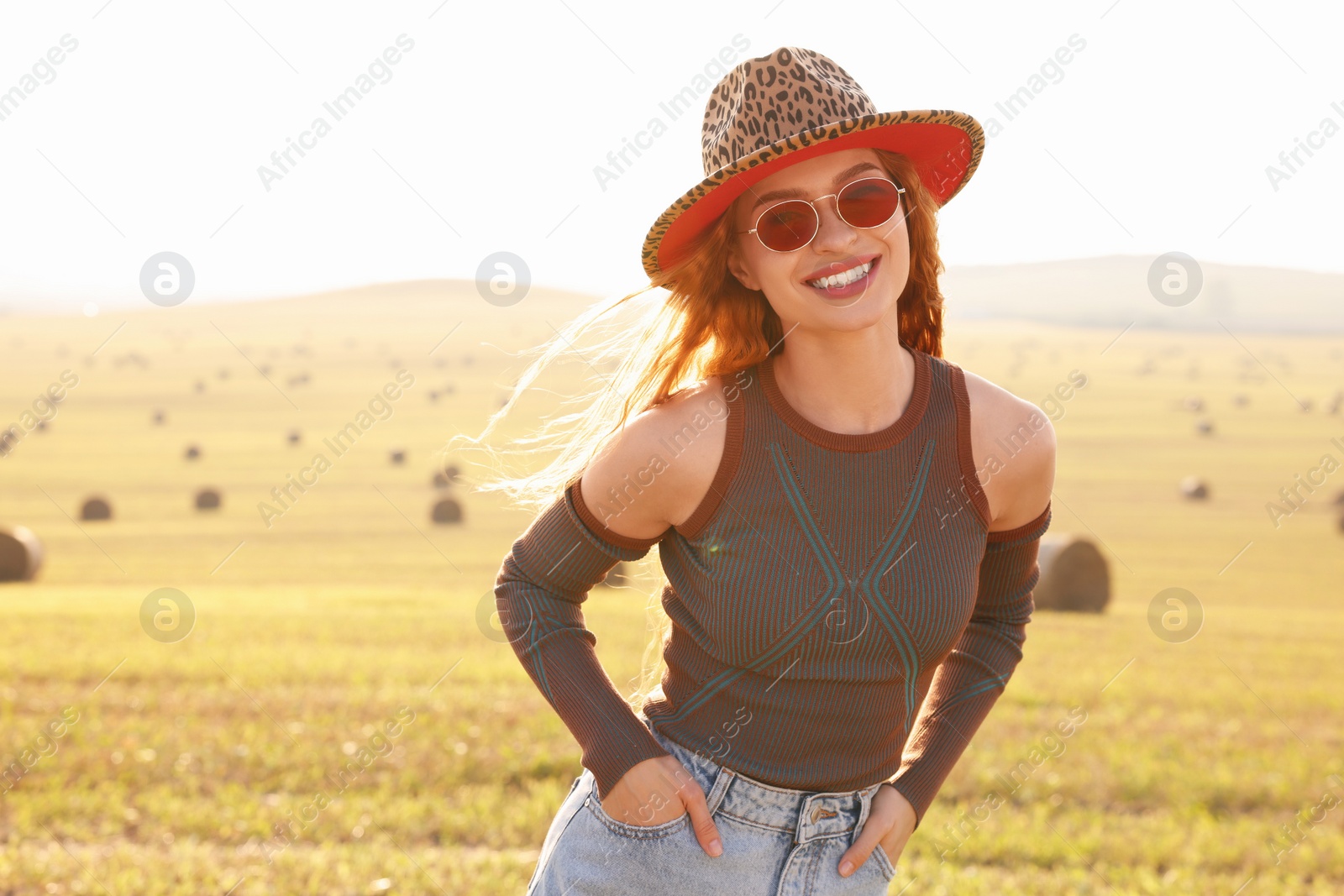 Photo of Beautiful happy hippie woman in hat in field, space for text