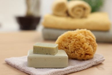 Photo of Soap bars and natural sponge on light wooden table, closeup. Spa therapy