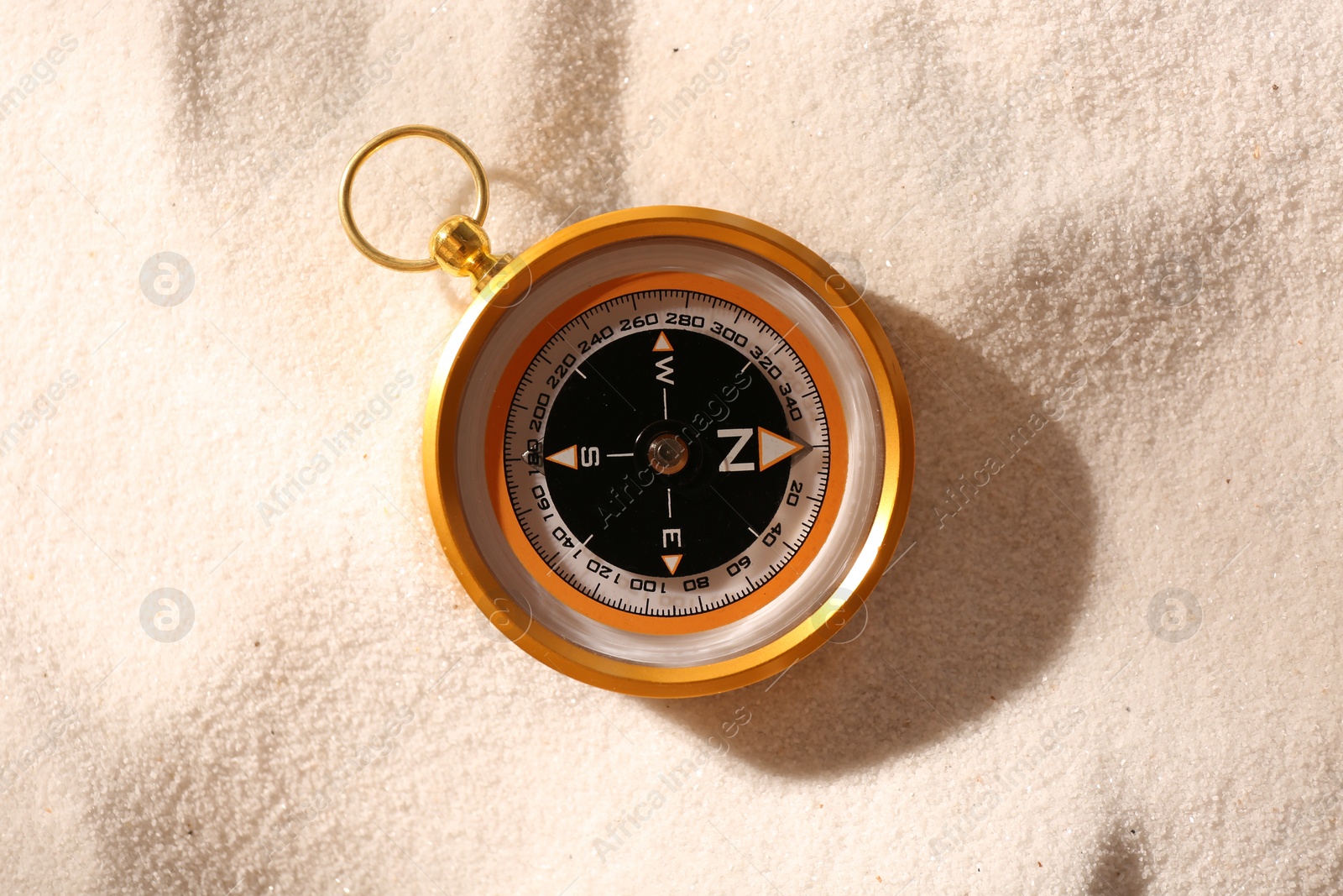 Photo of Compass on sand, top view. Navigation equipment