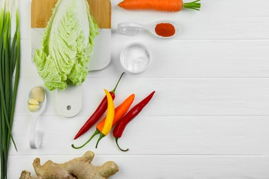 Flat lay composition with fresh Chinese cabbages and ingredients on white wooden table. Space for text