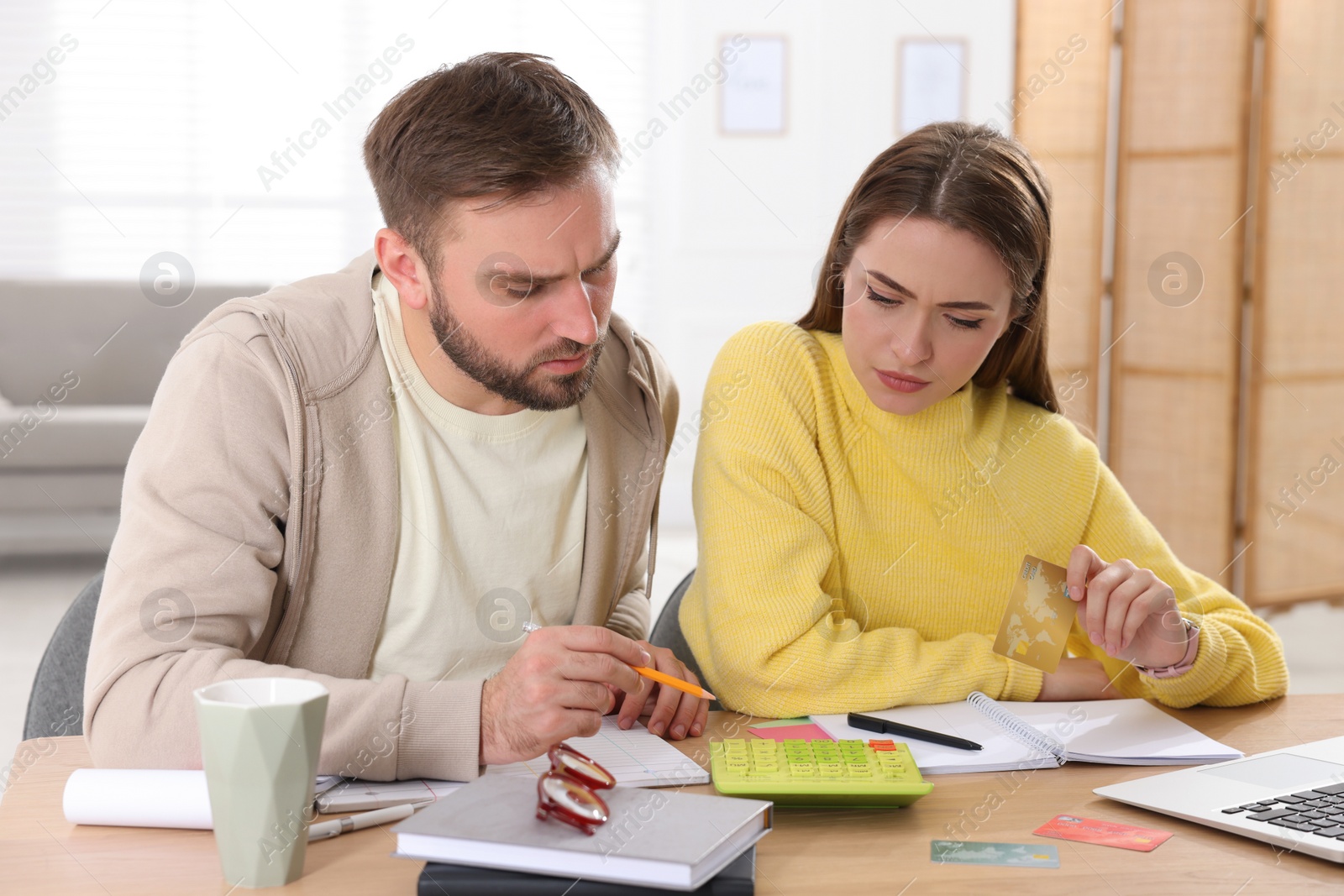 Photo of Young couple discussing family budget at table in living room