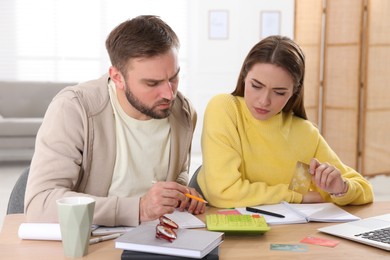 Young couple discussing family budget at table in living room