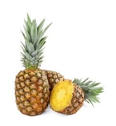 Whole and cut tasty ripe pineapples isolated on white