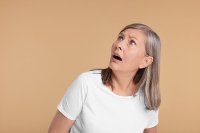 Photo of Portrait of surprised senior woman on beige background, space for text