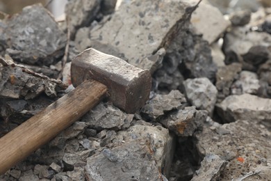 Sledgehammer on pile of broken stones outdoors, closeup