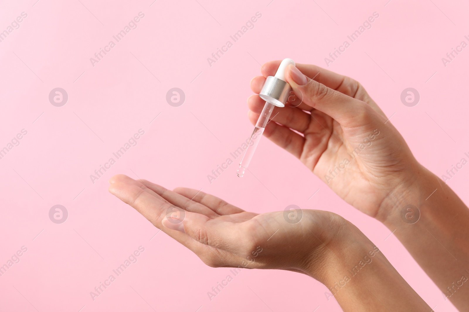 Photo of Woman applying cosmetic serum onto her hand on pink background, closeup. Space for text