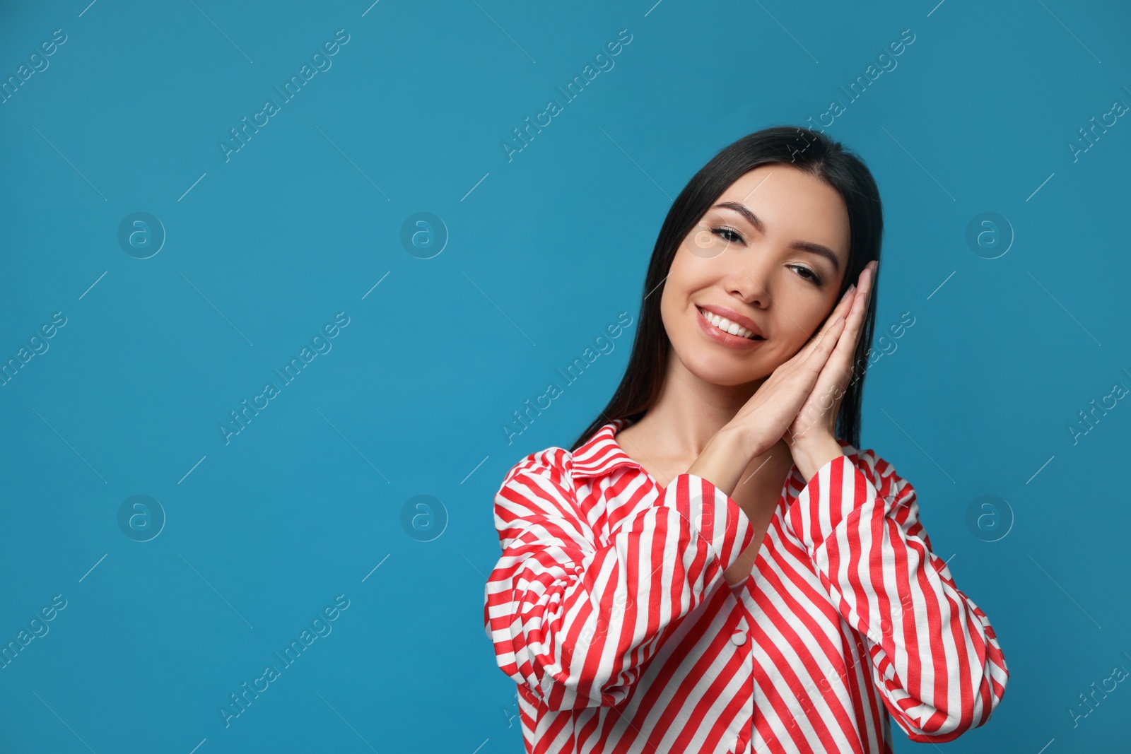 Photo of Beautiful Asian woman wearing pajamas on blue background, space for text. Bedtime