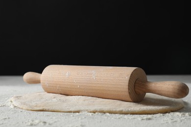 Photo of Raw dough and rolling pin on table