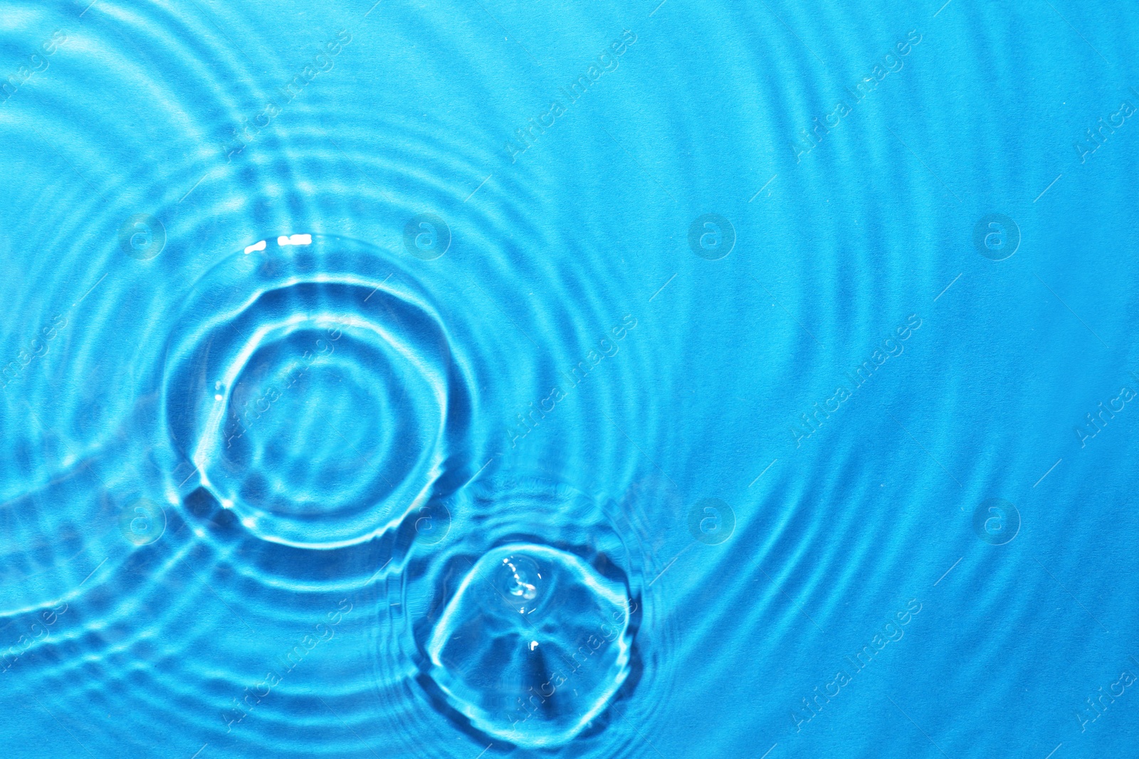 Image of Rippled surface of clear water on light blue background, top view