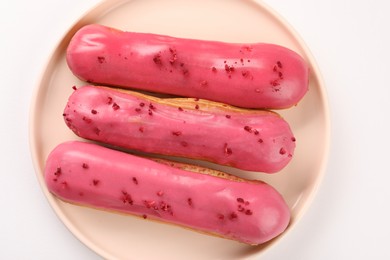 Delicious eclairs covered with glaze on white background, top view