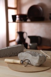 Clay and modeling tool on wooden table in workshop