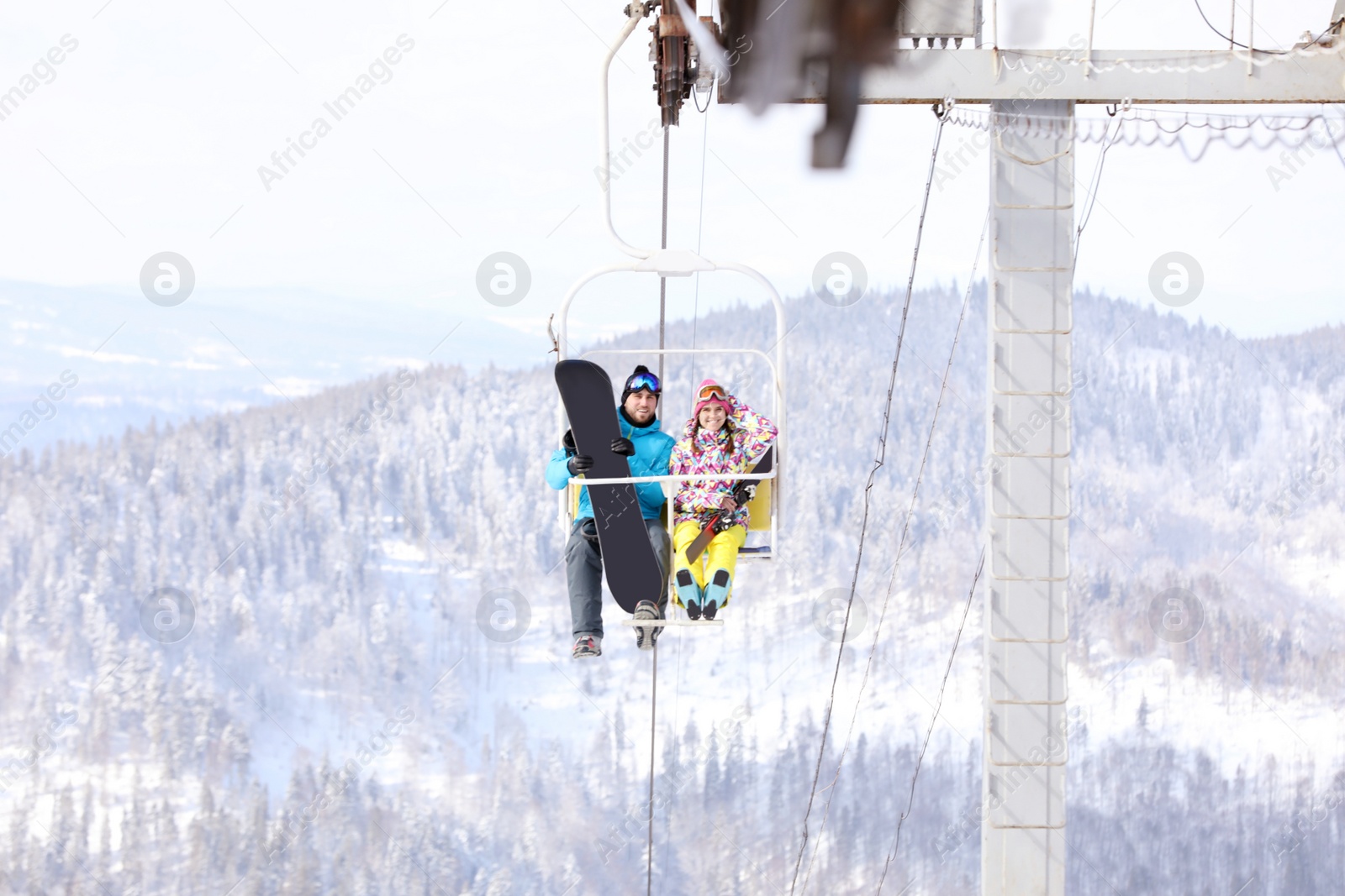 Photo of Couple using chairlift at mountain ski resort. Winter vacation