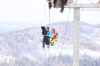 Couple using chairlift at mountain ski resort. Winter vacation