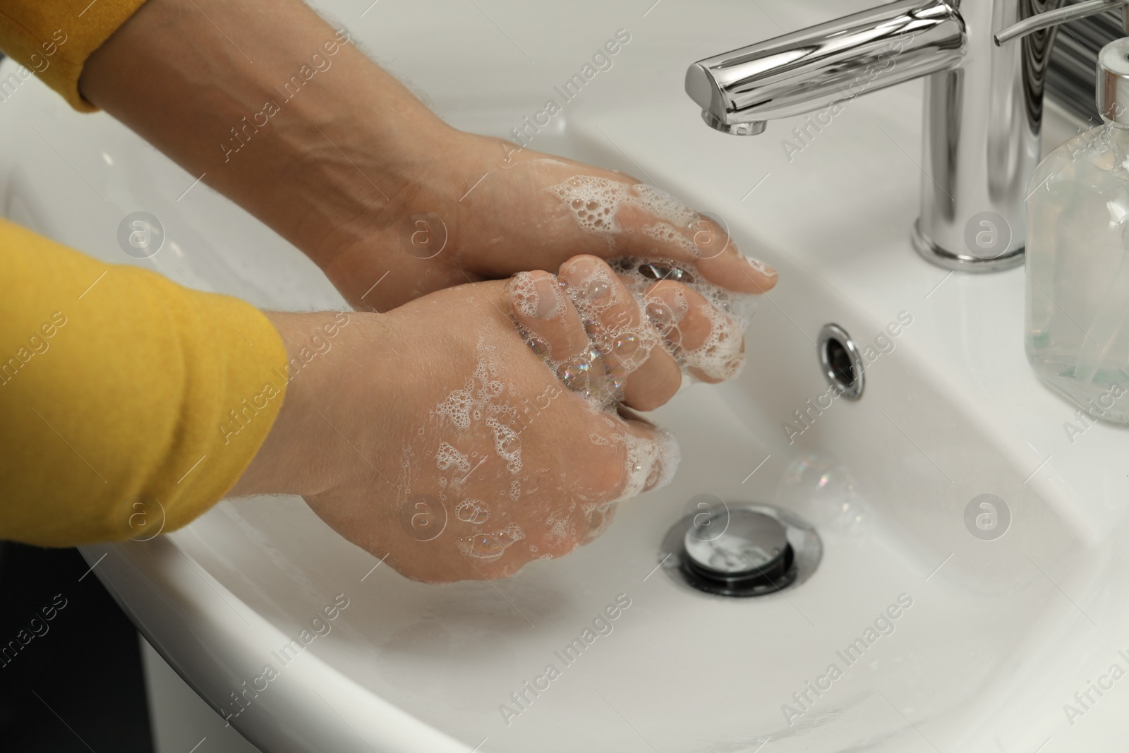 Photo of Man washing hands with soap over sink in bathroom, closeup