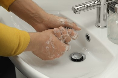 Photo of Man washing hands with soap over sink in bathroom, closeup