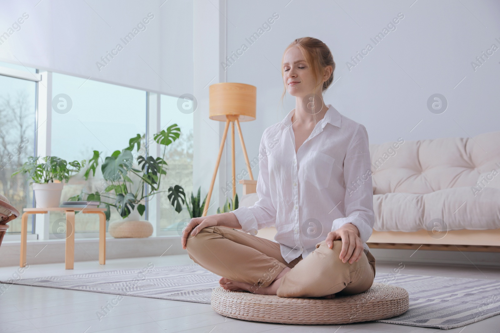 Photo of Woman meditating on wicker mat at home