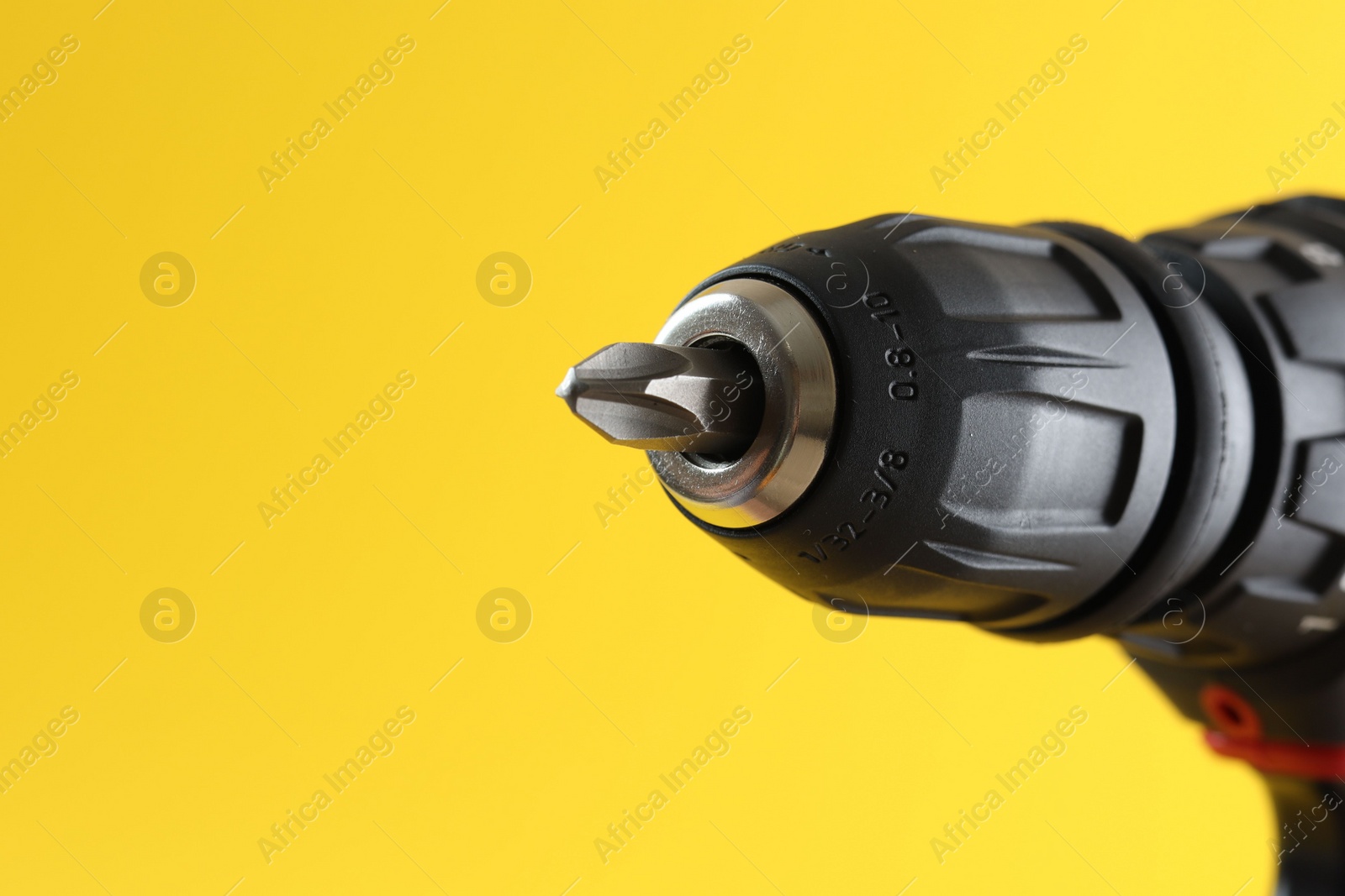 Photo of Modern electric screwdriver on yellow background, closeup. Space for text