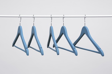 Empty clothes hangers on metal rail against light background