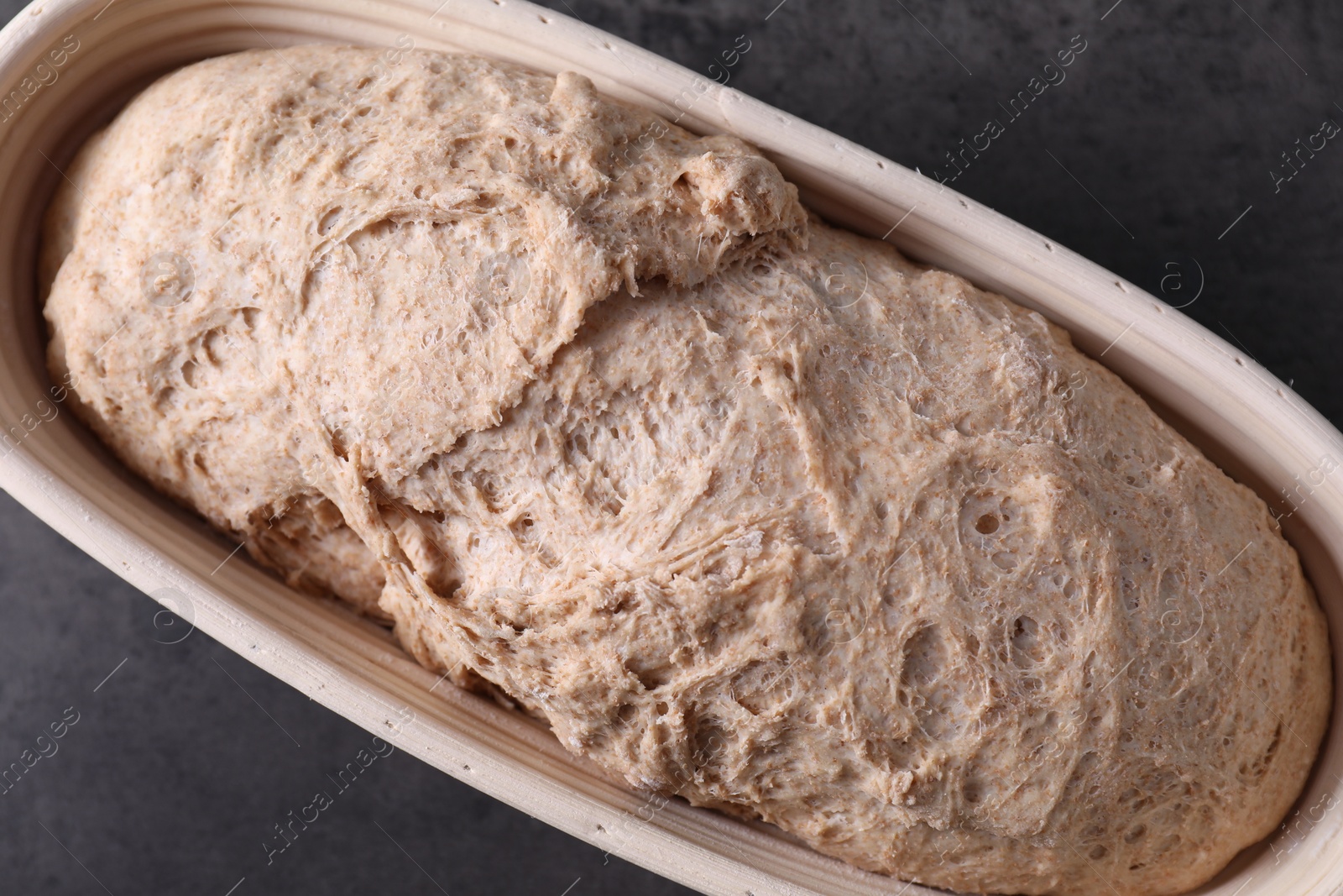 Photo of Fresh sourdough in proofing basket on grey table, top view