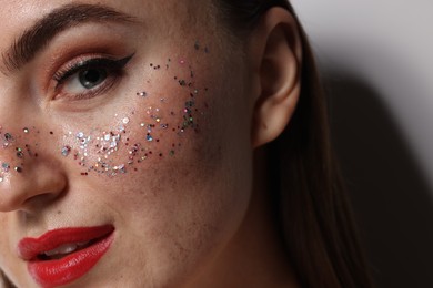 Photo of Beautiful woman with glitter freckles on grey background, closeup
