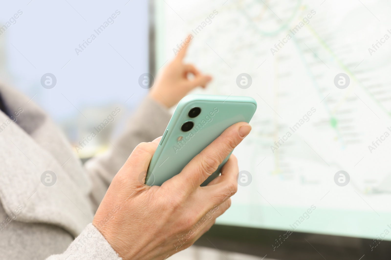 Photo of Woman with smartphone studying public transport map outdoors, closeup