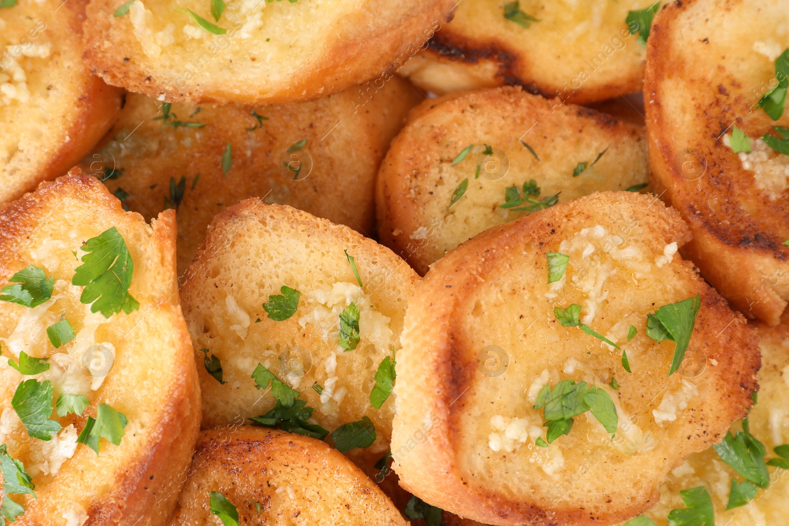 Photo of Slices of delicious toasted bread with garlic and herbs, closeup