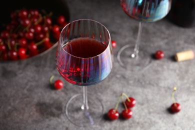 Photo of Delicious cherry wine and ripe juicy berries on grey table