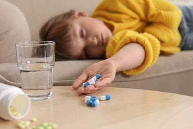 Unconscious little child with pills on sofa at home. Danger of medicament intoxication