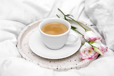 Photo of Tray with cup of coffee and flowers on white bed