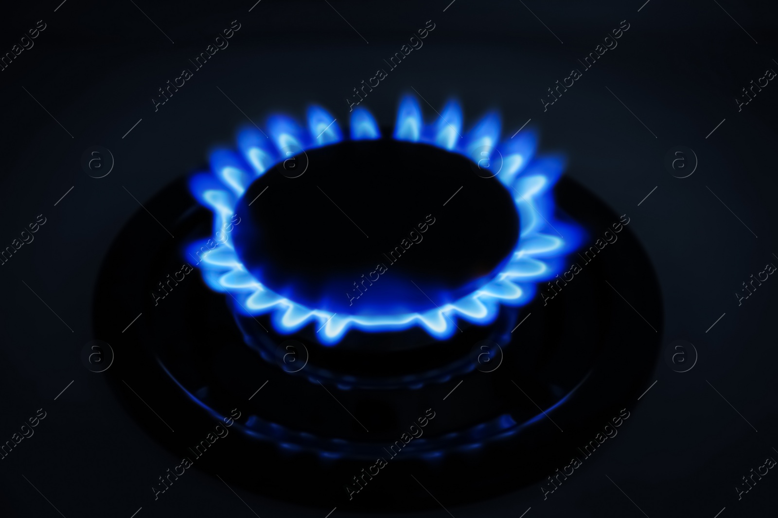 Photo of Gas burner of modern stove with burning blue flame at night