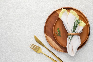 Photo of Stylish setting with cutlery, napkin, rosemary and plates on light textured table, flat lay. Space for text