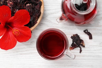 Delicious hibiscus tea and flowers on white wooden table, flat lay