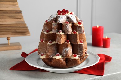 Delicious Pandoro Christmas tree cake with powdered sugar and berries near festive decor on white marble table
