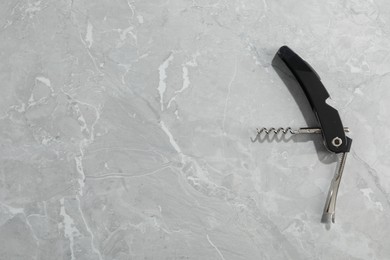 Photo of One corkscrew (sommelier knife) on grey marble table, top view. Space for text