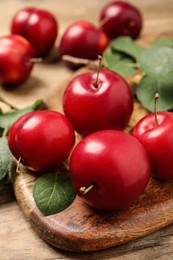 Delicious ripe cherry plums with leaves on wooden table, closeup