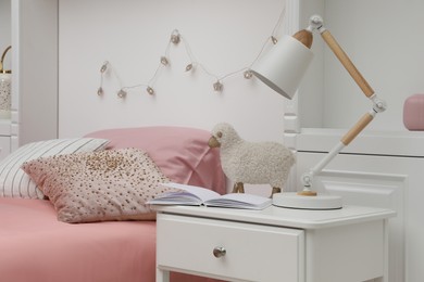 Lamp on white nightstand in cozy bedroom