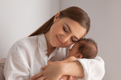 Mother holding her cute newborn baby indoors