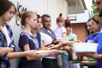 Photo of Poor people receiving food from volunteers outdoors