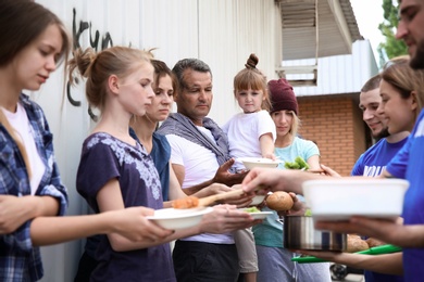 Poor people receiving food from volunteers outdoors