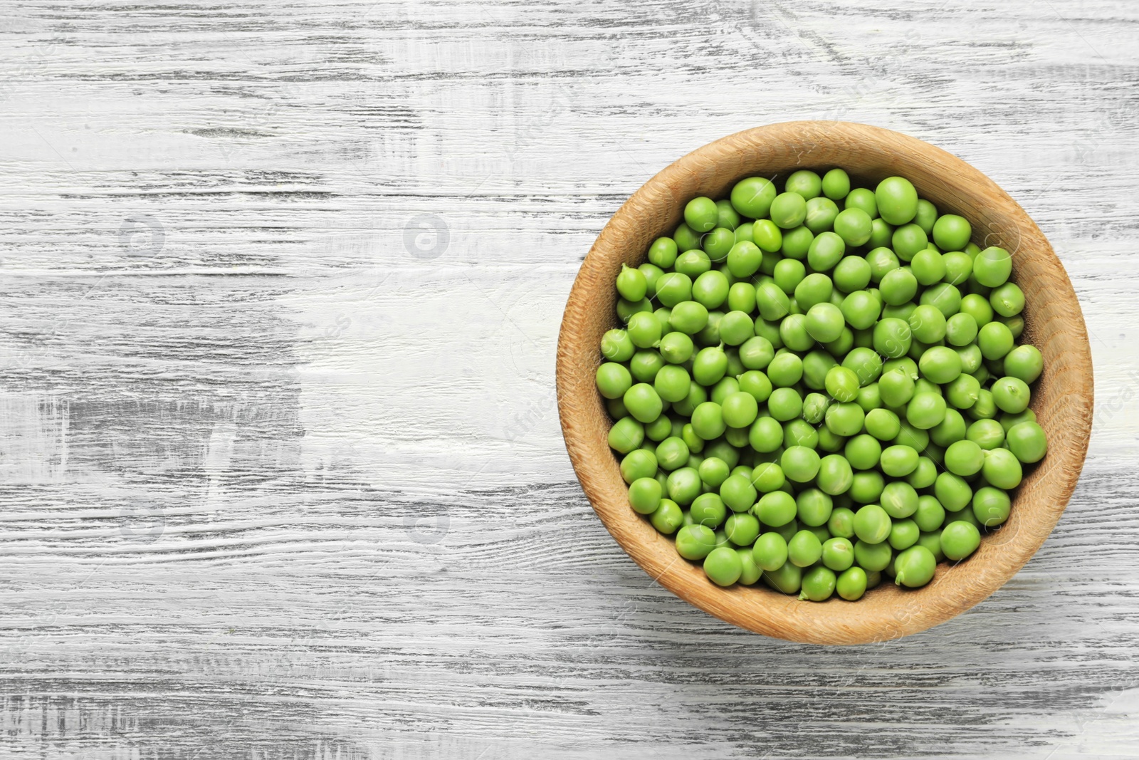 Photo of Plate with green peas on wooden background, top view