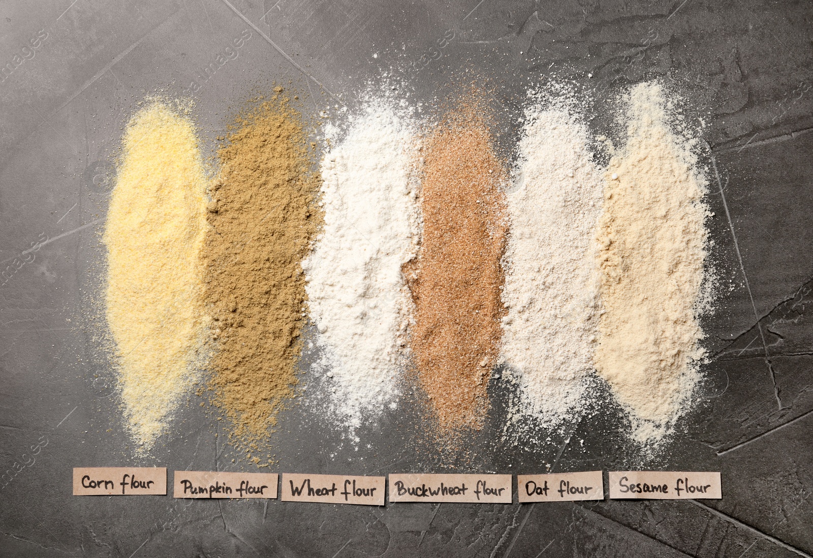 Photo of Stripes of different flour types and tags on grey table, top view