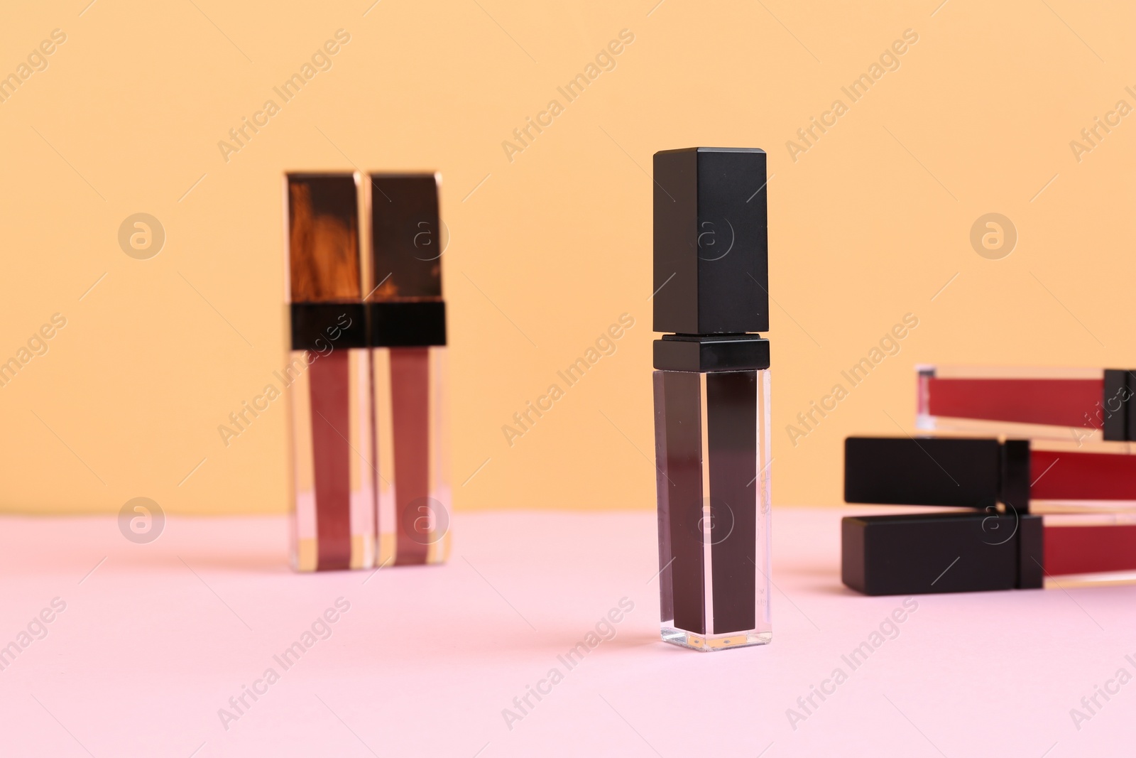 Photo of Many different lip glosses on color background