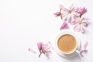Photo of Beautiful pink magnolia flowers and cup of aromatic coffee on white background, top view