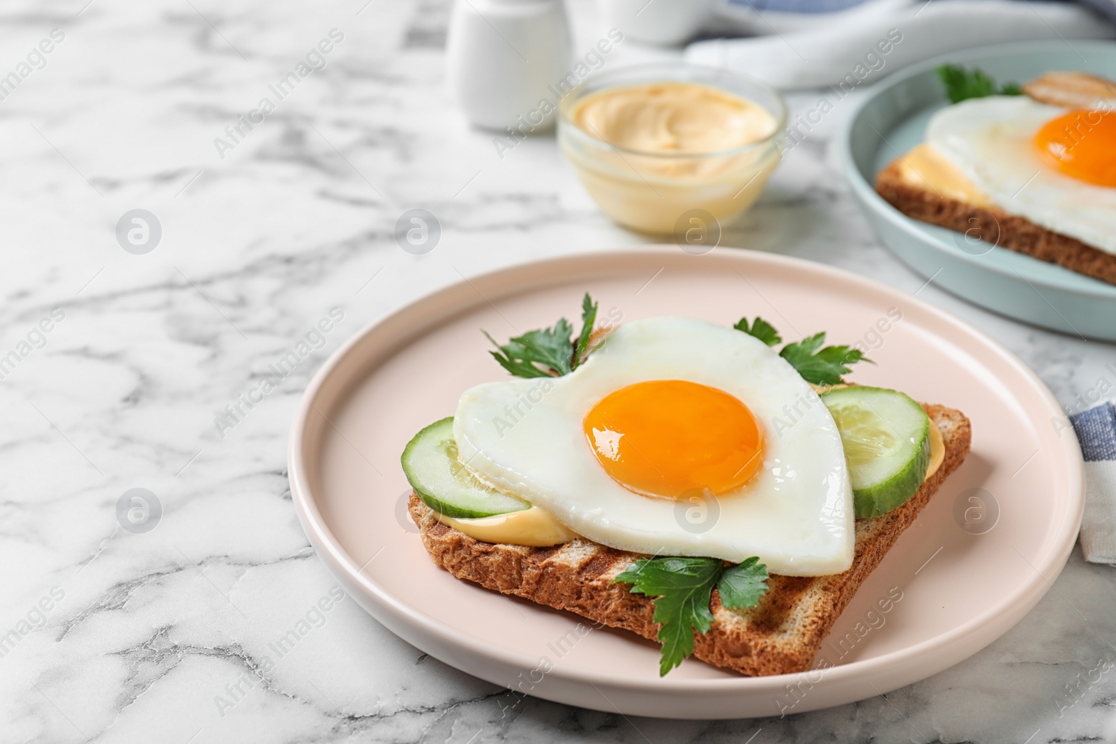 Photo of Plate of tasty sandwich with heart shaped fried egg on white marble table