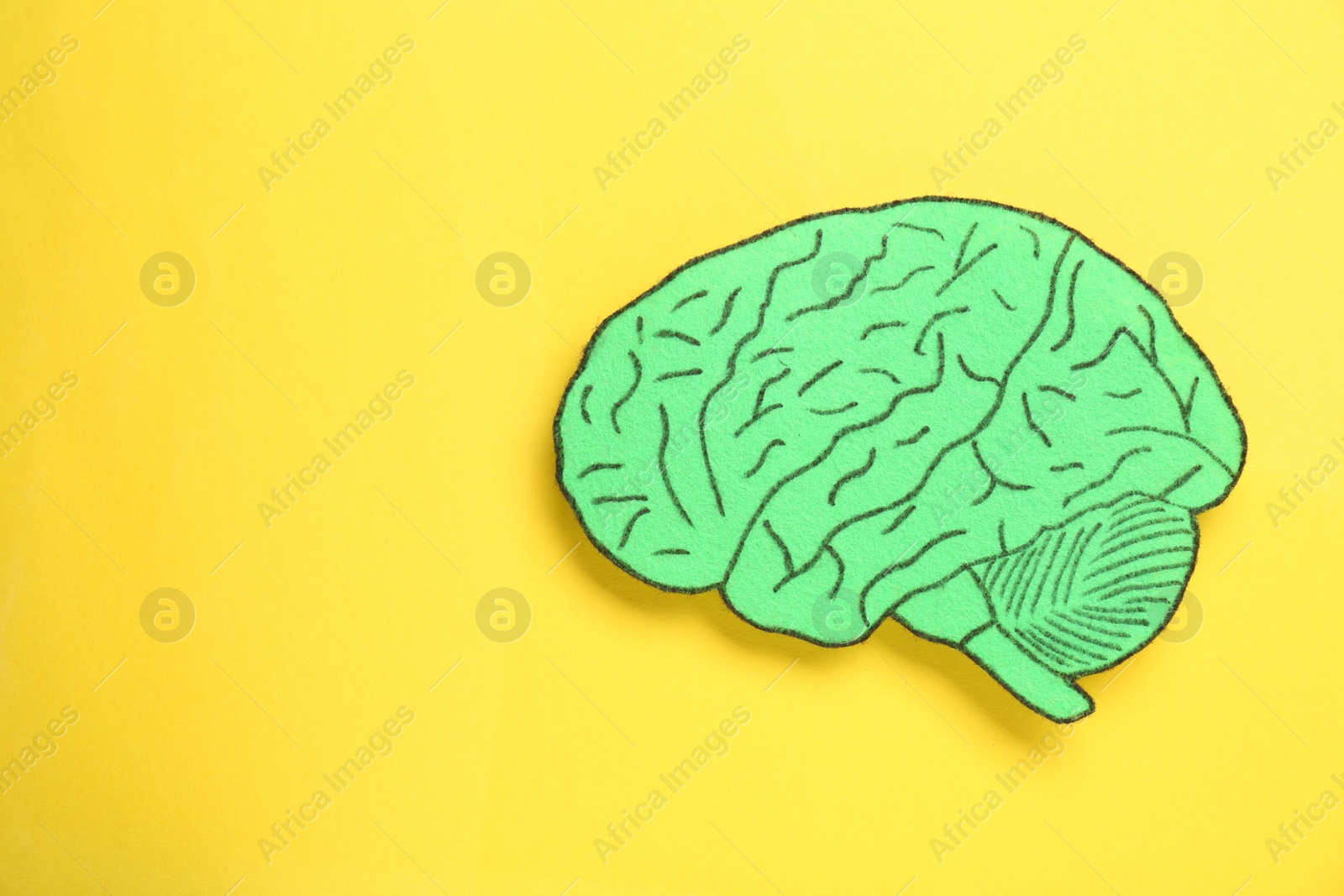 Photo of Paper cutout of human brain on yellow background, top view. Space for text