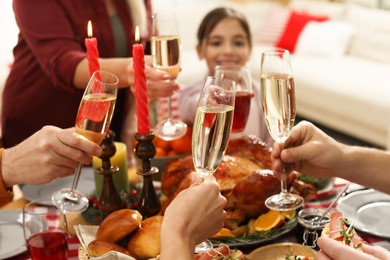 Photo of Family clinking glasses of drinks at festive dinner, focus on hands. Christmas celebration