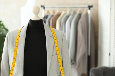 Photo of Mannequin with jacket and measuring tape in tailor shop, space for text