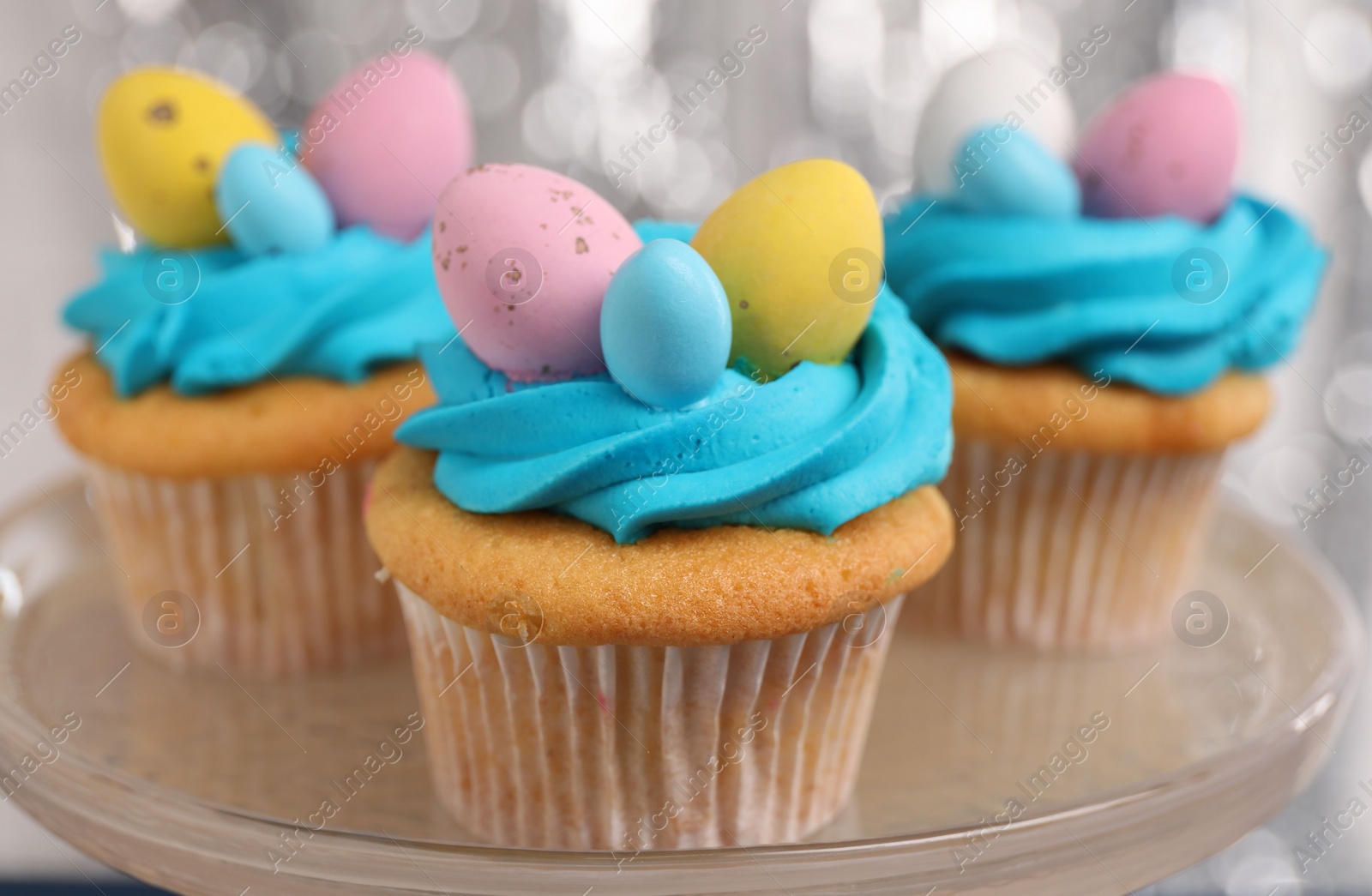 Photo of Tasty decorated Easter cupcakes on stand, closeup