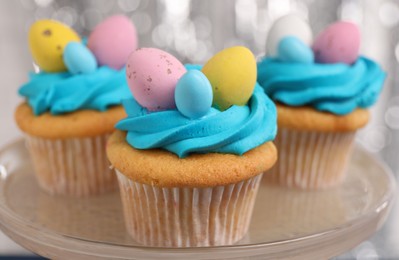 Photo of Tasty decorated Easter cupcakes on stand, closeup