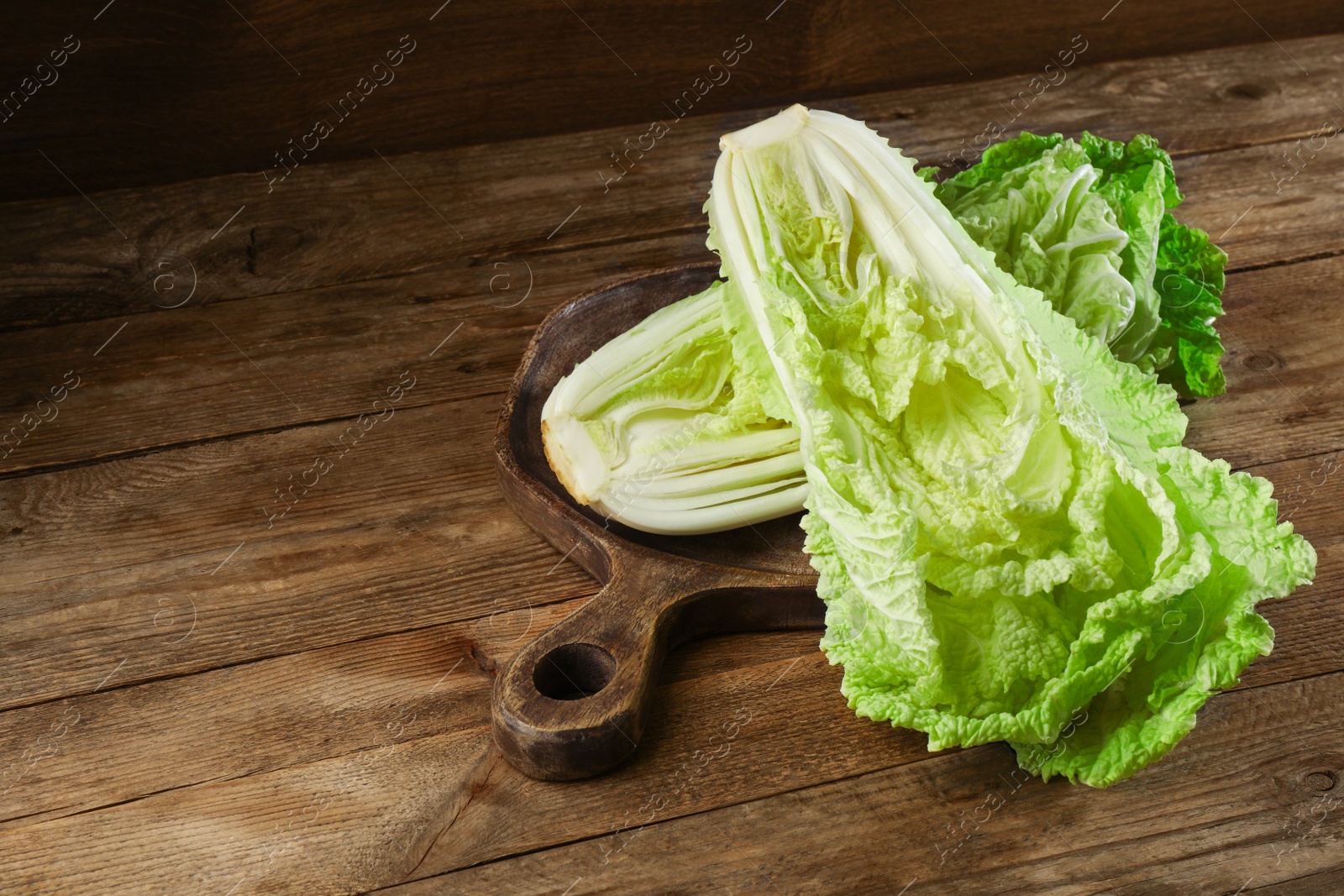 Photo of Halves of fresh ripe Chinese cabbage on wooden table